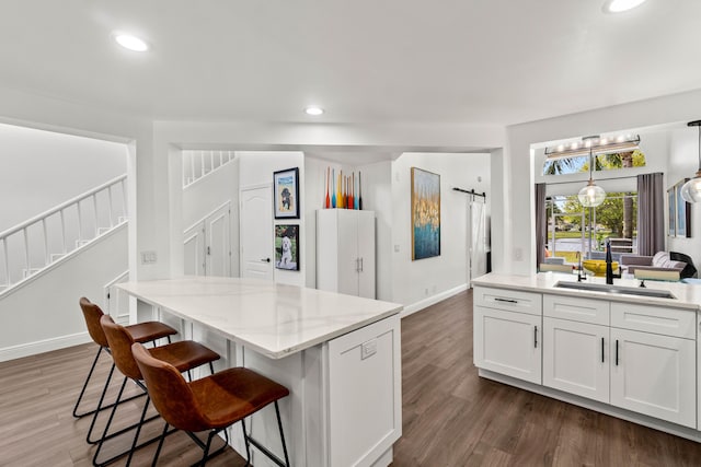 kitchen with dark wood-style floors, a kitchen bar, a sink, and recessed lighting