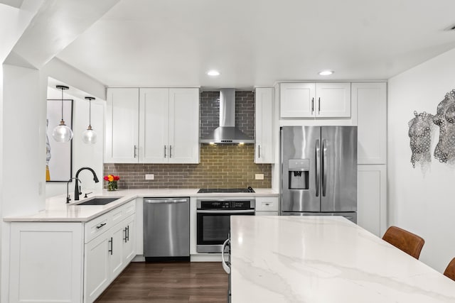 kitchen with appliances with stainless steel finishes, a sink, backsplash, and wall chimney exhaust hood