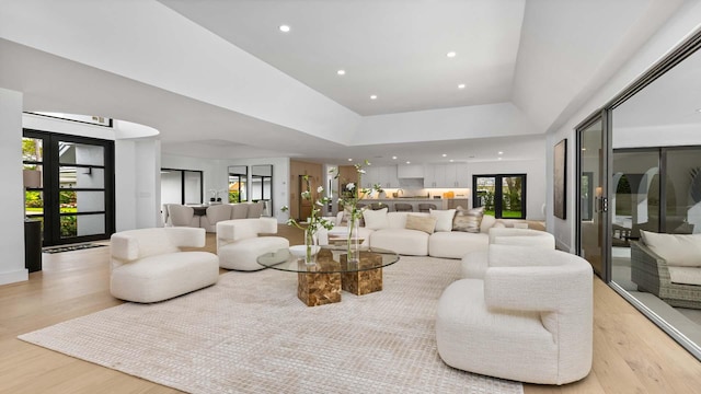 living area with a raised ceiling, recessed lighting, and light wood-type flooring