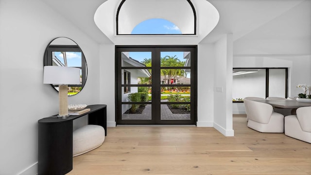 foyer featuring french doors, baseboards, and light wood finished floors