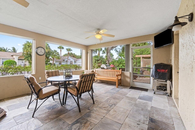 sunroom / solarium featuring a ceiling fan and plenty of natural light