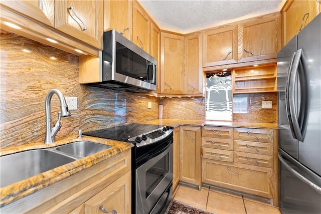 kitchen featuring a sink, light stone counters, backsplash, appliances with stainless steel finishes, and light tile patterned floors