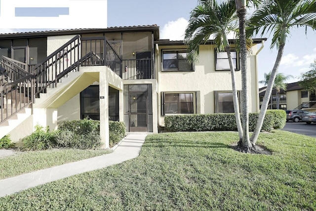 multi unit property with stairs, a front yard, and stucco siding