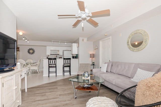 living room with visible vents, rail lighting, light wood-style flooring, and a ceiling fan