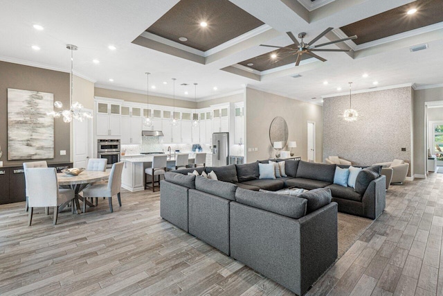 living room with recessed lighting, ceiling fan with notable chandelier, coffered ceiling, ornamental molding, and light wood finished floors