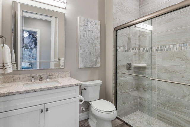 full bathroom featuring baseboards, toilet, a shower stall, and vanity