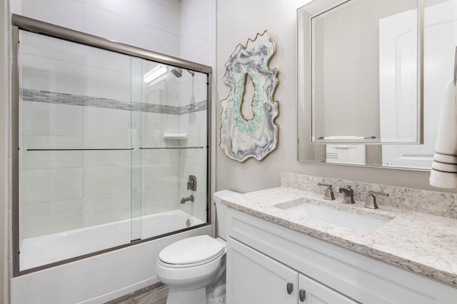 bathroom with wood finished floors, shower / bath combination with glass door, vanity, and toilet