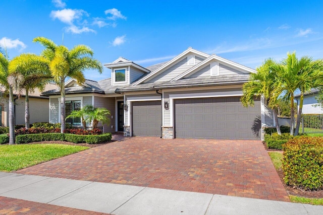 view of front of home featuring stone siding, decorative driveway, and an attached garage