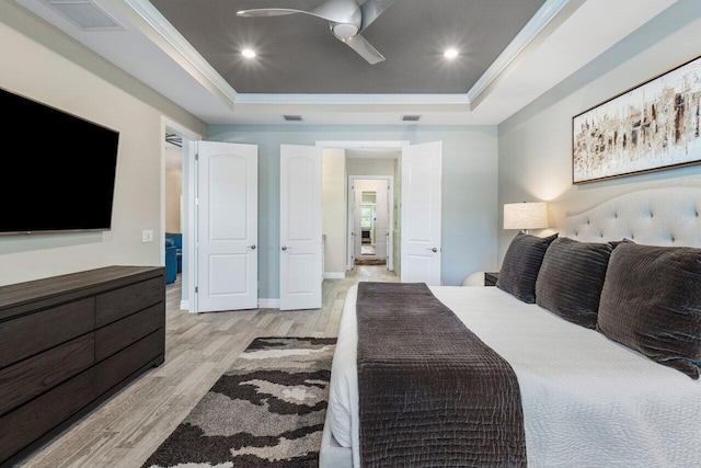 bedroom featuring light wood finished floors, visible vents, and a raised ceiling