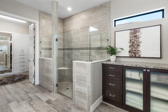 bathroom with a shower stall and wood finished floors