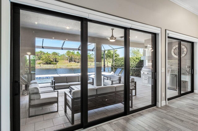 doorway to outside with crown molding, a water view, plenty of natural light, and light wood-style flooring