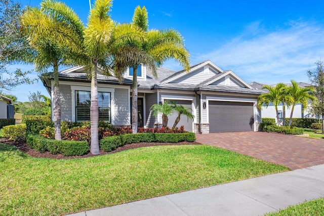 view of front of property with a garage, stone siding, a front lawn, and decorative driveway