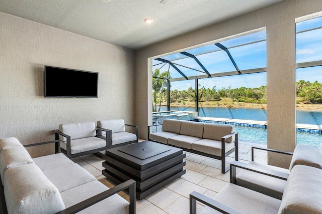 living area with a water view, a sunroom, a healthy amount of sunlight, and a textured wall