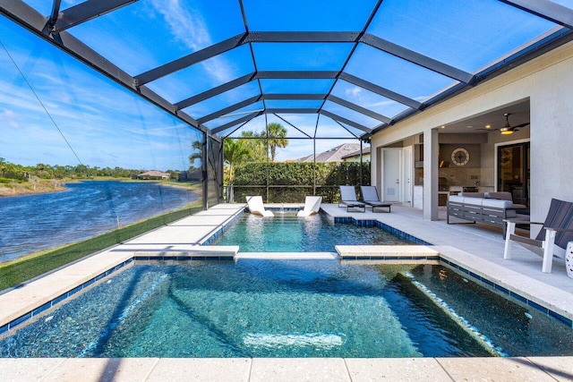 view of swimming pool featuring a water view, glass enclosure, a patio area, ceiling fan, and an outdoor living space