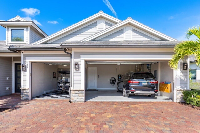 view of front of house with an attached garage, stone siding, and decorative driveway