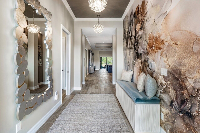 hall featuring ornamental molding, a notable chandelier, baseboards, and wood finished floors