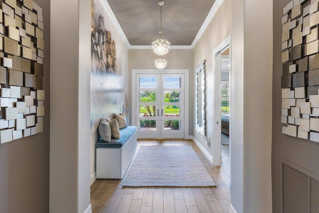 doorway with french doors, visible vents, ornamental molding, light wood-style floors, and a chandelier