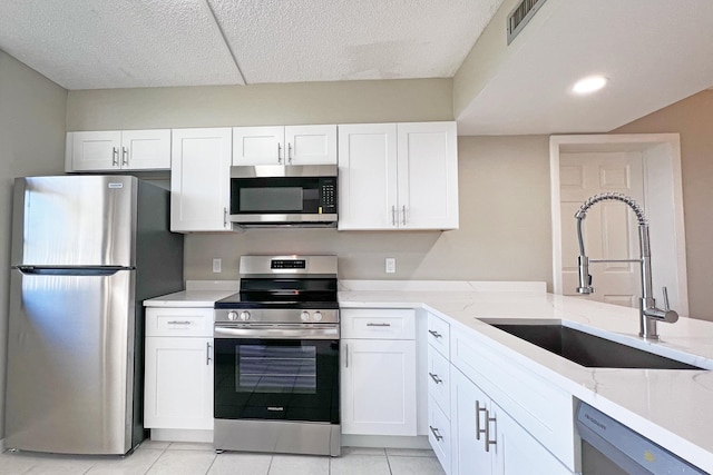 3636 Whitehall Dr Unit 402A, West Palm Beach, FL 33401 - kitchen with appliances with stainless steel finishes, a sink, white cabinetry, light stone counters, and light tile patterned floors