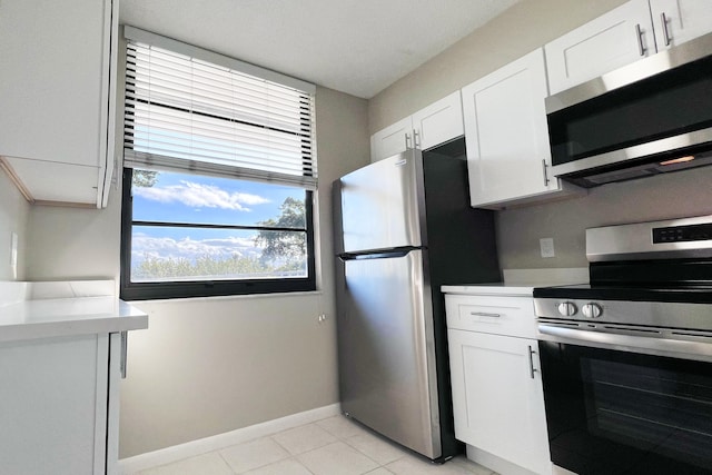 3636 Whitehall Dr Unit 402A, West Palm Beach, FL 33401 - kitchen with stainless steel appliances, light countertops, white cabinets, baseboards, and light tile patterned floors