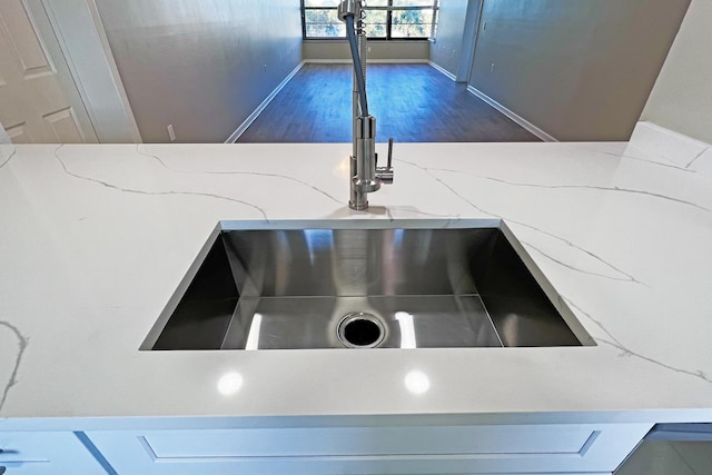 3636 Whitehall Dr Unit 402A, West Palm Beach, FL 33401 - kitchen view of a sink, wood finished floors, light stone counters, and baseboards