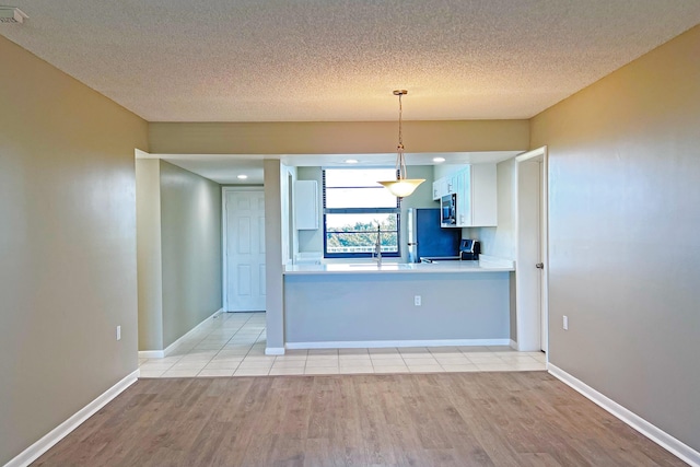 3636 Whitehall Dr Unit 402A, West Palm Beach, FL 33401 - kitchen with appliances with stainless steel finishes, light wood finished floors, white cabinets, a textured ceiling, and pendant lighting