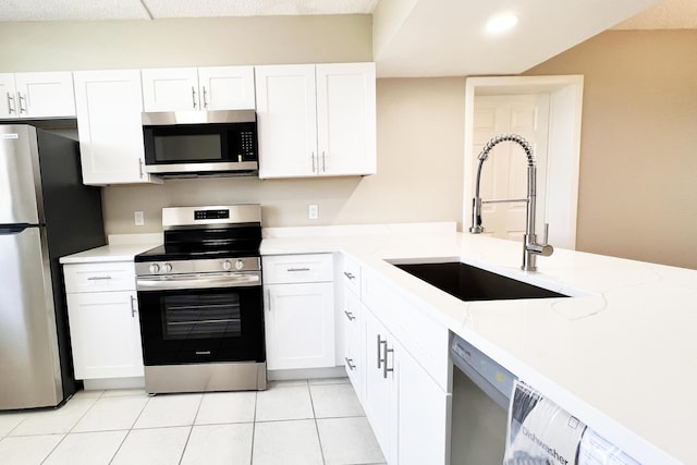 3636 Whitehall Dr Unit 402A, West Palm Beach, FL 33401 - kitchen featuring stainless steel appliances, a sink, white cabinetry, light tile patterned floors, and light stone countertops