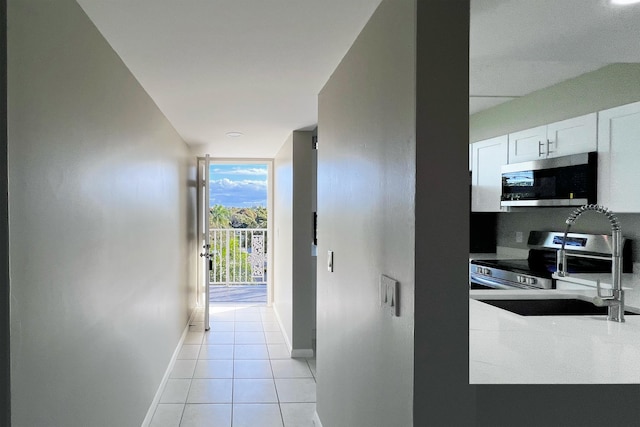 3636 Whitehall Dr Unit 402A, West Palm Beach, FL 33401 - hall featuring a sink, baseboards, light tile patterned flooring, and a wall of windows