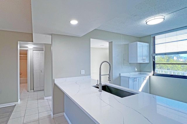 3636 Whitehall Dr Unit 402A, West Palm Beach, FL 33401 - kitchen featuring a sink, baseboards, light stone counters, light tile patterned floors, and a textured ceiling