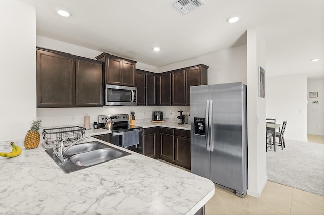 kitchen with a sink, visible vents, dark brown cabinets, appliances with stainless steel finishes, and light countertops