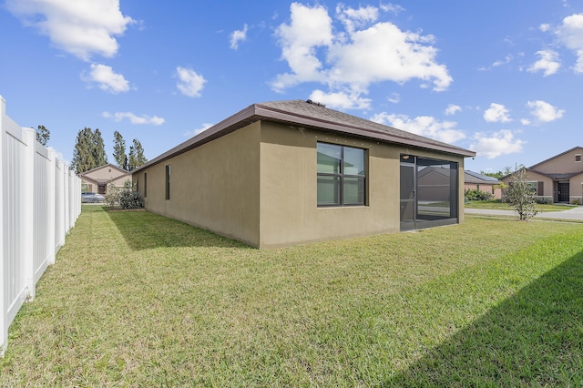 view of property exterior featuring a yard, fence, and stucco siding