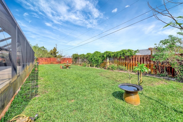 view of yard featuring glass enclosure and a fenced backyard