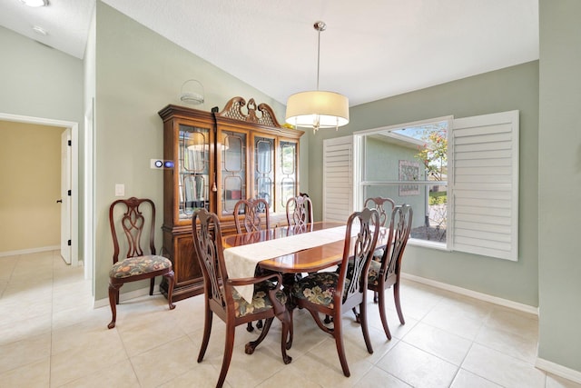 dining space featuring light tile patterned floors, baseboards, and vaulted ceiling