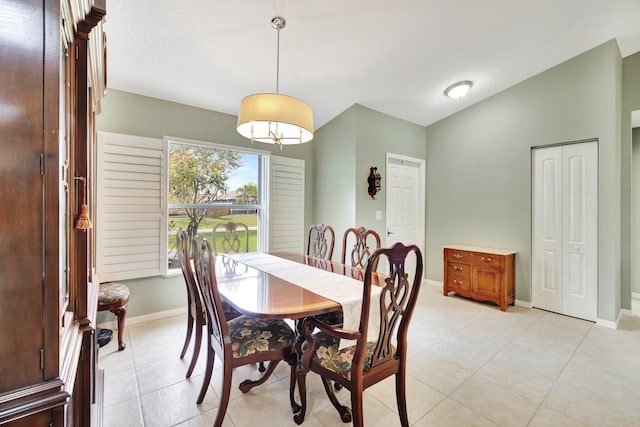 dining area with lofted ceiling, baseboards, and light tile patterned floors