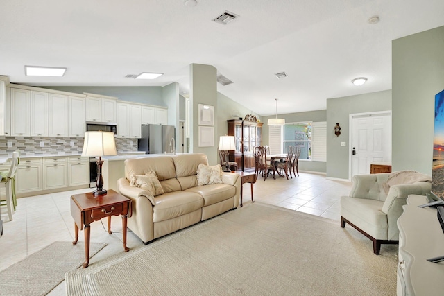 living area with lofted ceiling, visible vents, and light tile patterned floors