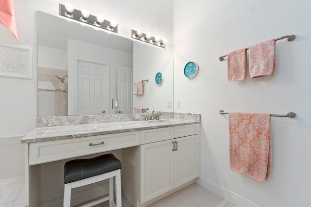 full bath with tile patterned flooring, baseboards, tiled shower, and vanity