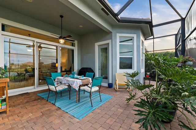 view of patio with a ceiling fan, outdoor dining space, and a lanai