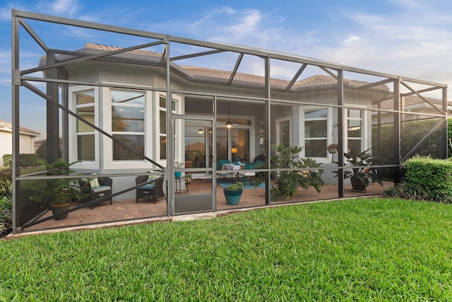 back of property with a lanai, a patio, and a lawn