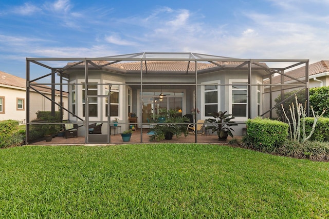 back of house with glass enclosure, a yard, a patio, and a ceiling fan