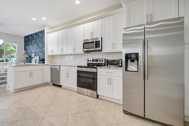 kitchen with light stone countertops, white cabinetry, appliances with stainless steel finishes, and backsplash