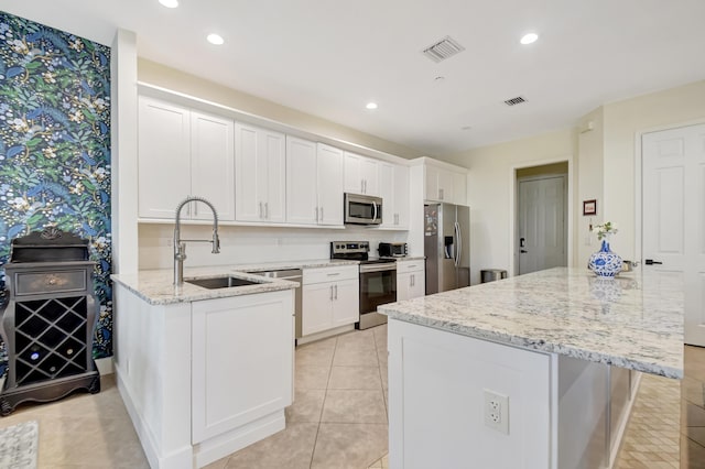 kitchen featuring a sink, visible vents, white cabinetry, appliances with stainless steel finishes, and light stone countertops