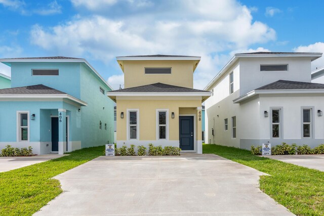 view of front of property with a front yard, roof with shingles, and stucco siding