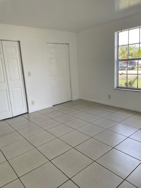 unfurnished bedroom with a closet, baseboards, and light tile patterned floors