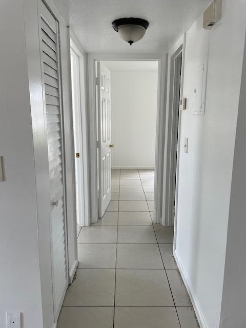 corridor with light tile patterned flooring and baseboards