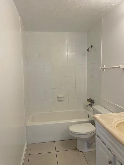 full bathroom featuring shower / washtub combination, toilet, vanity, a textured ceiling, and tile patterned flooring