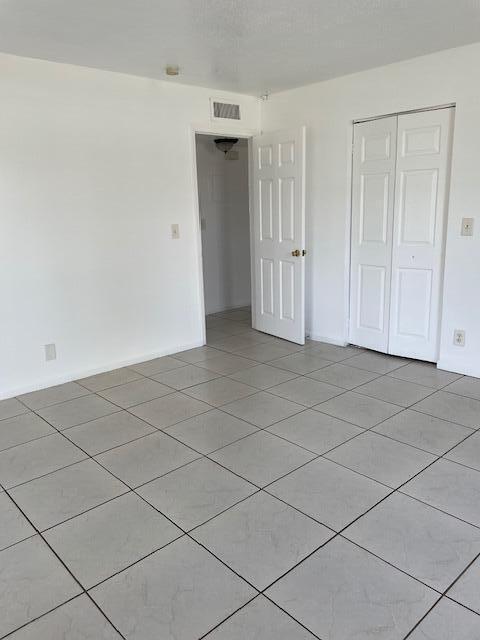 unfurnished bedroom with baseboards, visible vents, a closet, and light tile patterned flooring