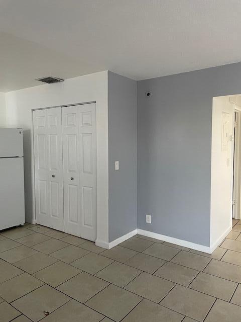 unfurnished bedroom with visible vents, a closet, freestanding refrigerator, and baseboards