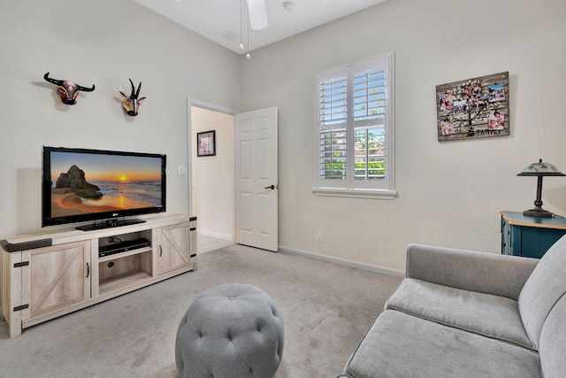 living room with baseboards, a ceiling fan, and light colored carpet