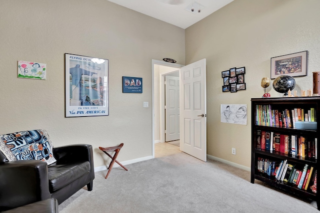 sitting room with baseboards and light colored carpet