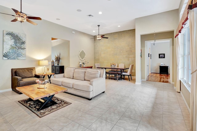 living room featuring baseboards, light tile patterned flooring, visible vents, and a ceiling fan