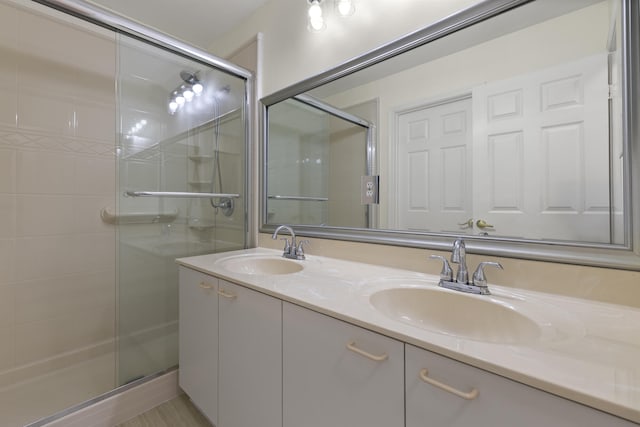 full bathroom with a stall shower, a sink, and double vanity